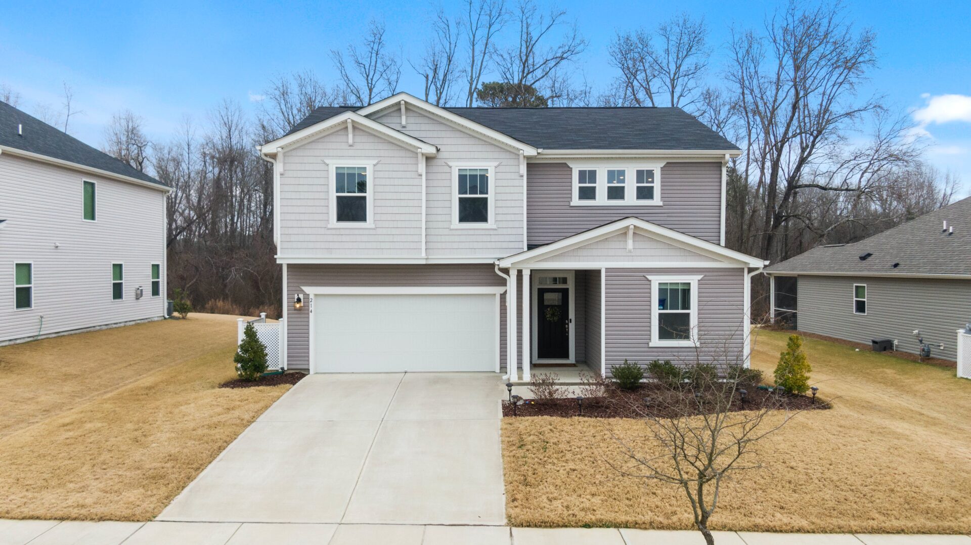 A house with a driveway and trees in the background